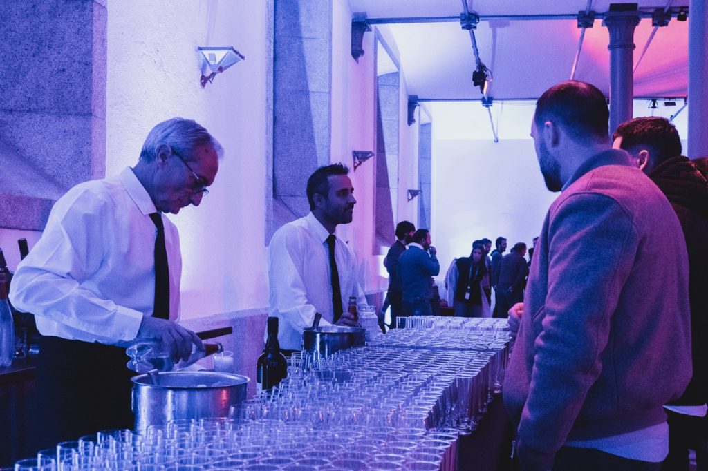 welcome drink em festa de natal de empresa na alfândega do porto. funcionários de catering a servir bebidas atrás de uma mesa com copos vazios.