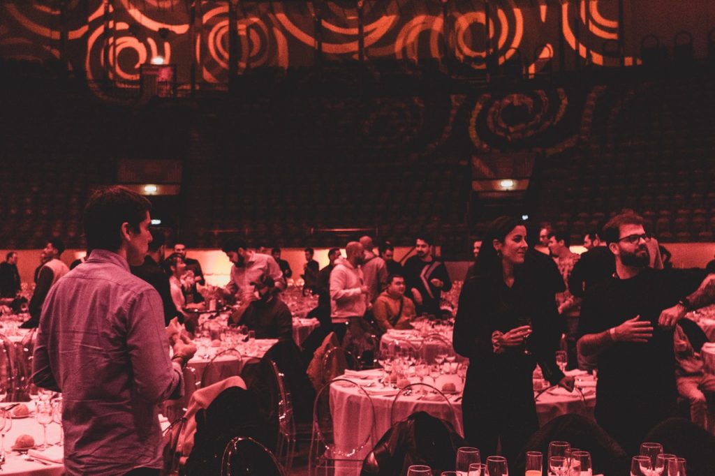 pessoas a sentarem-se para jantar de empresa no campo pequeno. decoração de evento feita com videomapping.