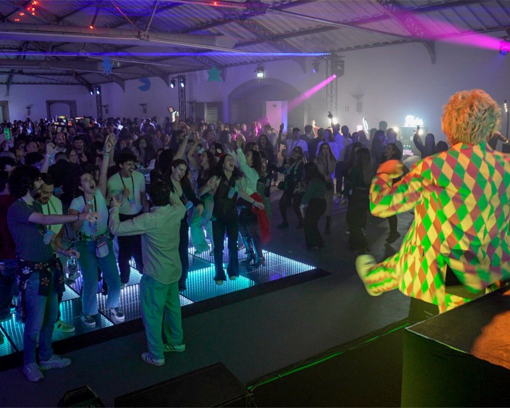 Grupo de funcionários Blip a dançar em pista de dança LED. Atuação Dupla Mete Cá Sets. Evento corporativo. Jantar de Natal de empresa.