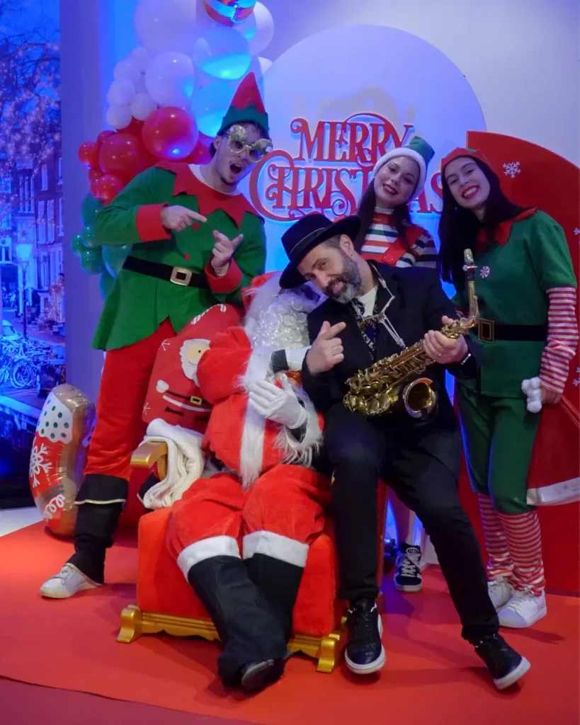 Saxofonista Pai Natal e Elfos a tirar fotografia em evento de natal corporativo. Saxofonista eventos. Aluger trono de Pai Natal eventos. Decoração natalícia.